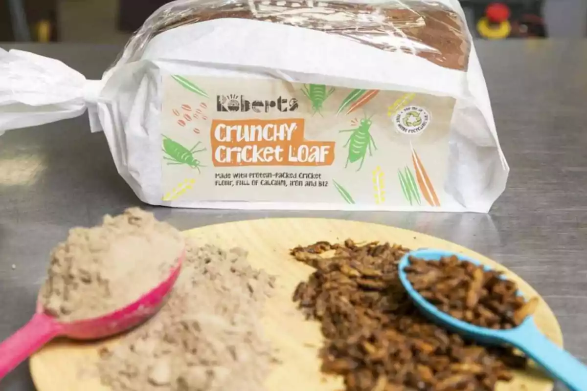 Sliced bread wrapped with a label that says Crunchy Cricket Loaf, accompanied by flour and dried crickets on a board